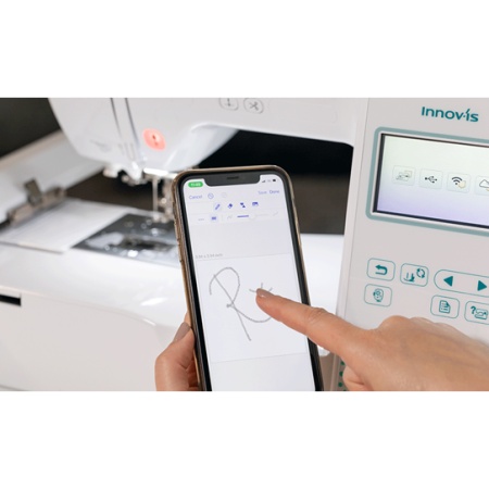 Image of a phone being held and a design being drawn, in front of the F540E machine.