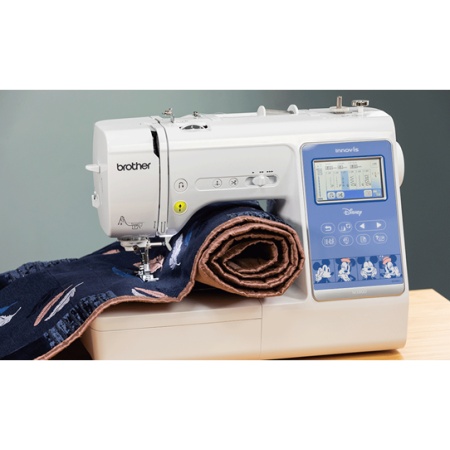 Brother Innov-is M380D with a quilt rolled up on the sewing bed, set on a table ready to sew.