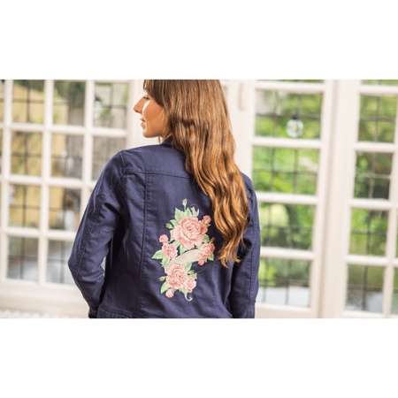 woman wearing a denim jacket that has been embroidered with a floral design created on the Brother PR1 embroidery machine