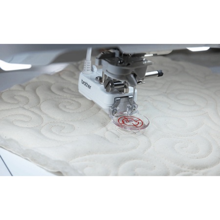 Free motion quilting on off white fabric in swirling pattern