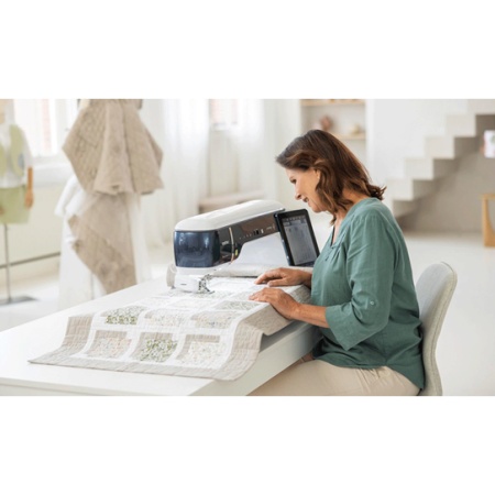 Person sat at a table with the Brother EV1 machine sewing a large quilt
