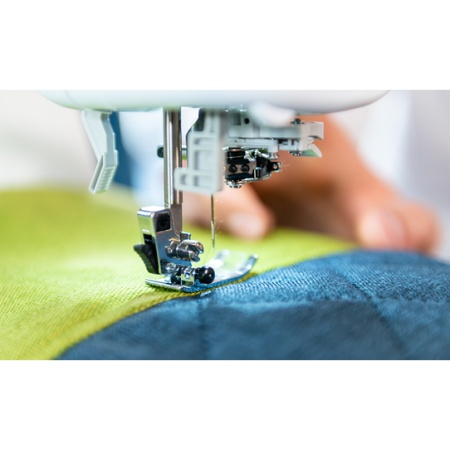 Sewing machine presser foot, threaded and sewing some colourful fabric